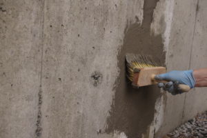 A person is applying a Kryton repair solution to a concrete surface.