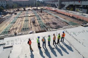 Several construction workers face toward the sun at a construction site.