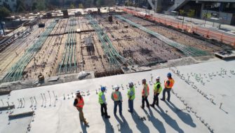 Several construction workers face toward the sun at a construction site.