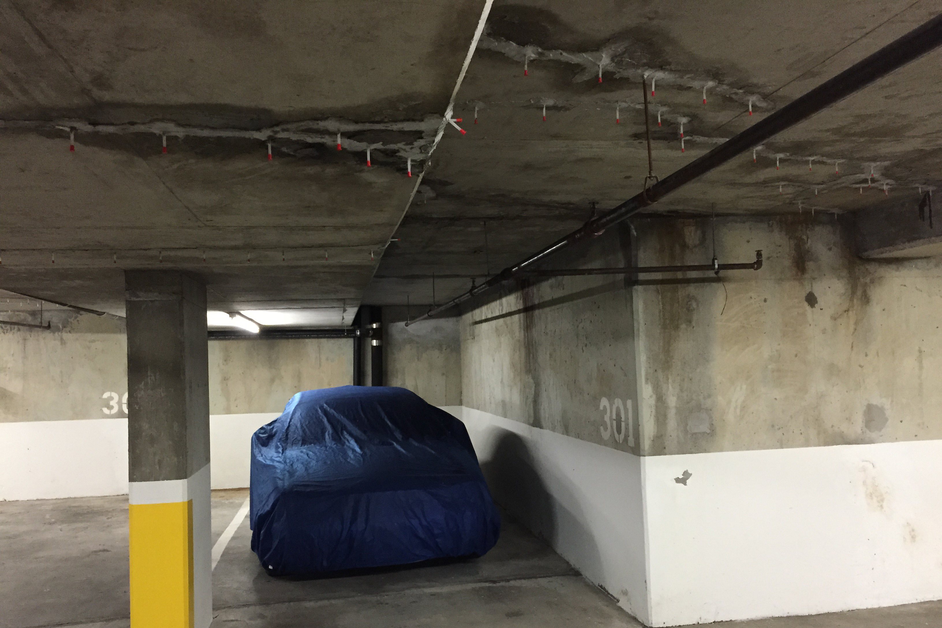 An unsightly epoxy injection has been done on concrete cracks in the ceiling of an underground parking lot.