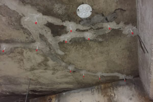 Epoxy injections have been used in cracks on a concrete ceiling in an attempt to repair them.