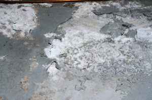 A basement floor with white stuff on concrete that has been caused by efflorescence.