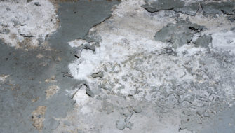 A basement floor with white stuff on concrete that has been caused by efflorescence.