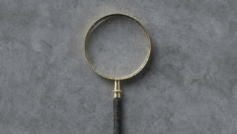 A magnifying glass is on a concrete floor, waiting to help someone take a closer look at the white stuff on their concrete.