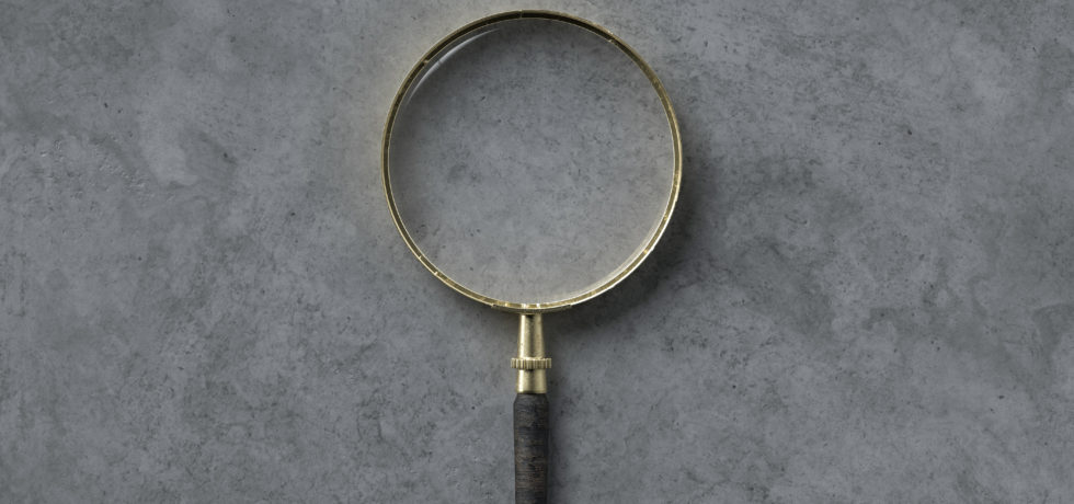 A magnifying glass is on a concrete floor, waiting to help someone take a closer look at the white stuff on their concrete.