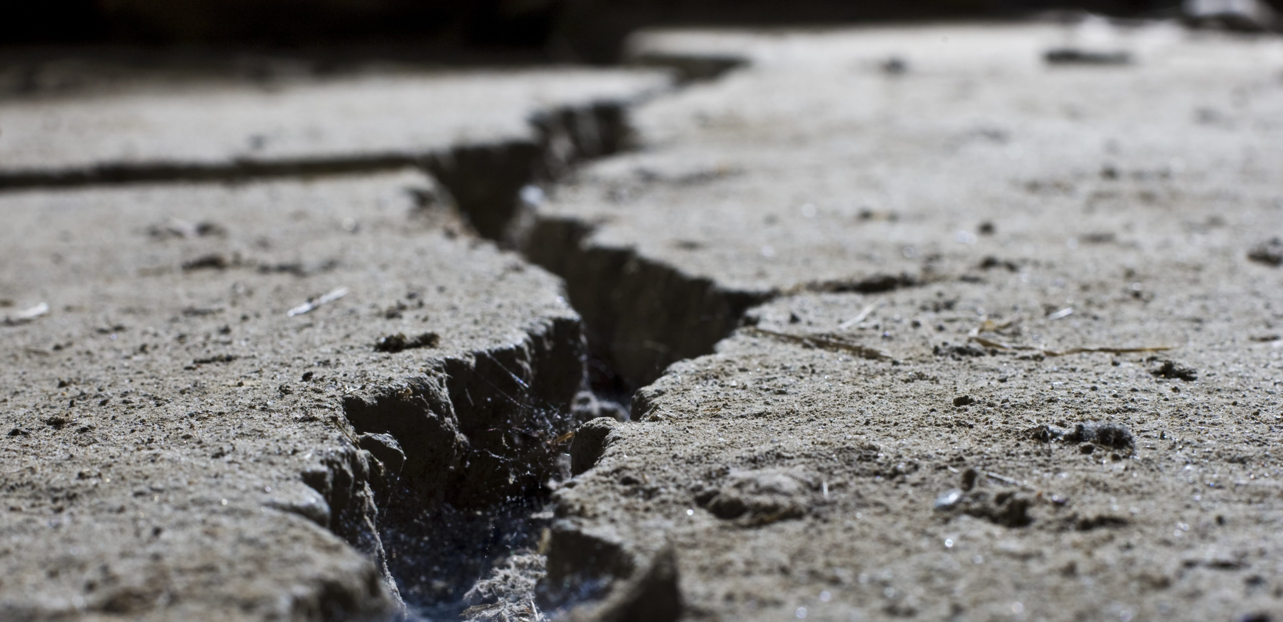 A large crack is splitting a concrete floor in two.