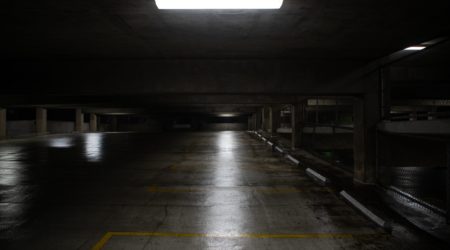 Some lights dimly shine on a dark parking garage.