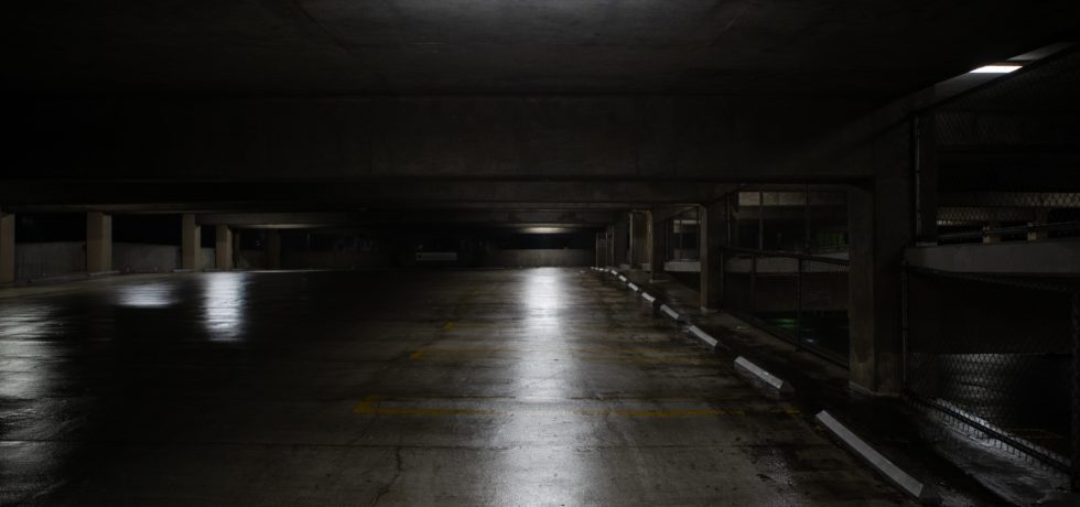 Some lights dimly shine on a dark parking garage.