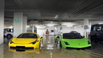 Two neon-colored cars are parked in a flooding parking garage.