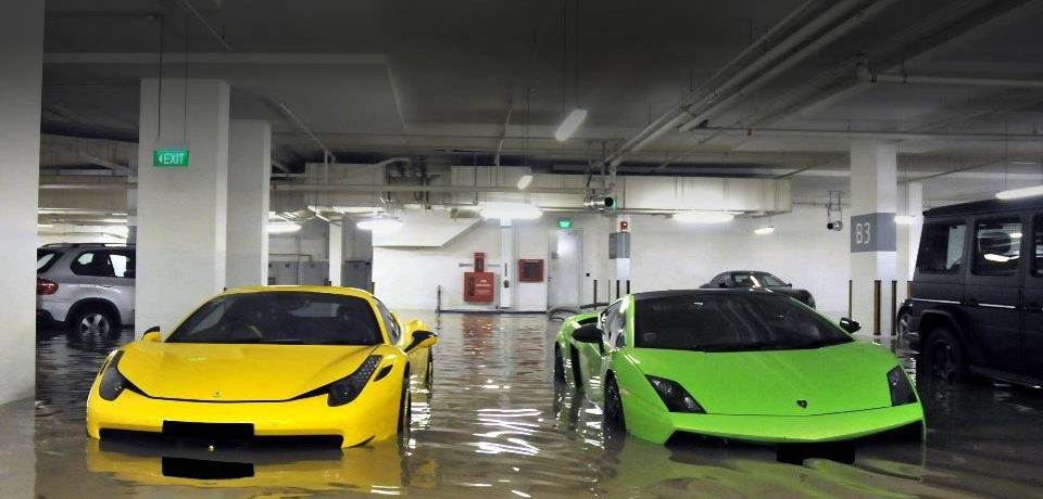 Two neon-colored cars are parked in a flooding parking garage.