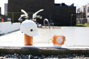 A white hard hat is sitting on an orange pole next to a Maturix Sensor with sparks shooting up from behind.