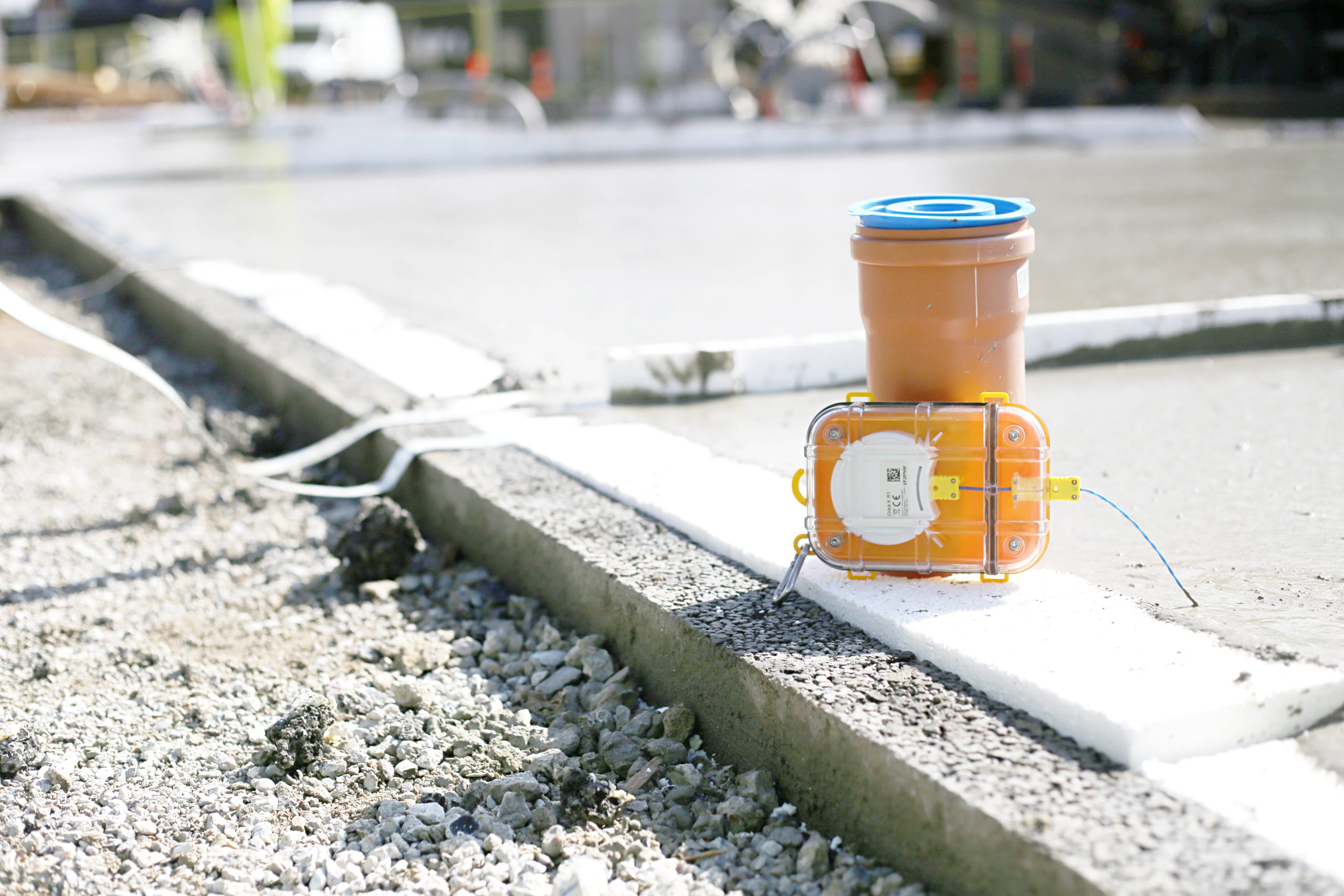 A Maturix Smart Concrete Sensor is resting against an orange pole in a construction site.