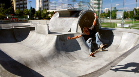A young man skateboards off the edge of a concrete surface in Metro Skate Park.