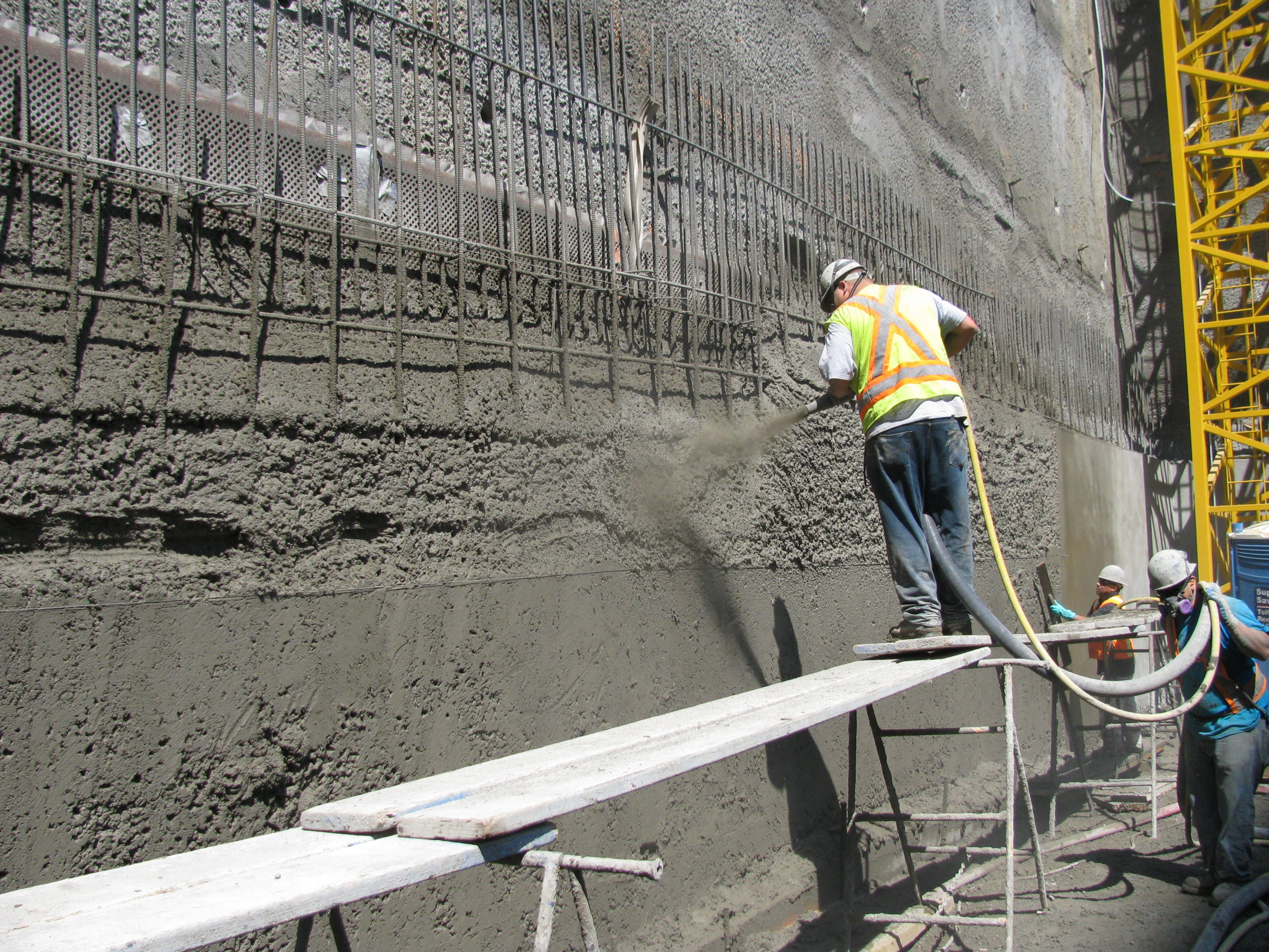 A construction worker is applying shotcrete with Smart Concrete technology.
