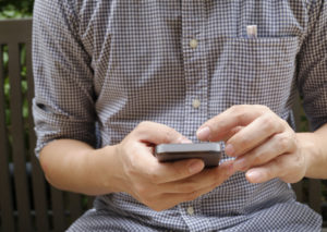 Man wearing plaid shirt is using his smart phone.
