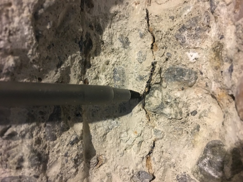 A pen is pointing out a crack in the concrete.