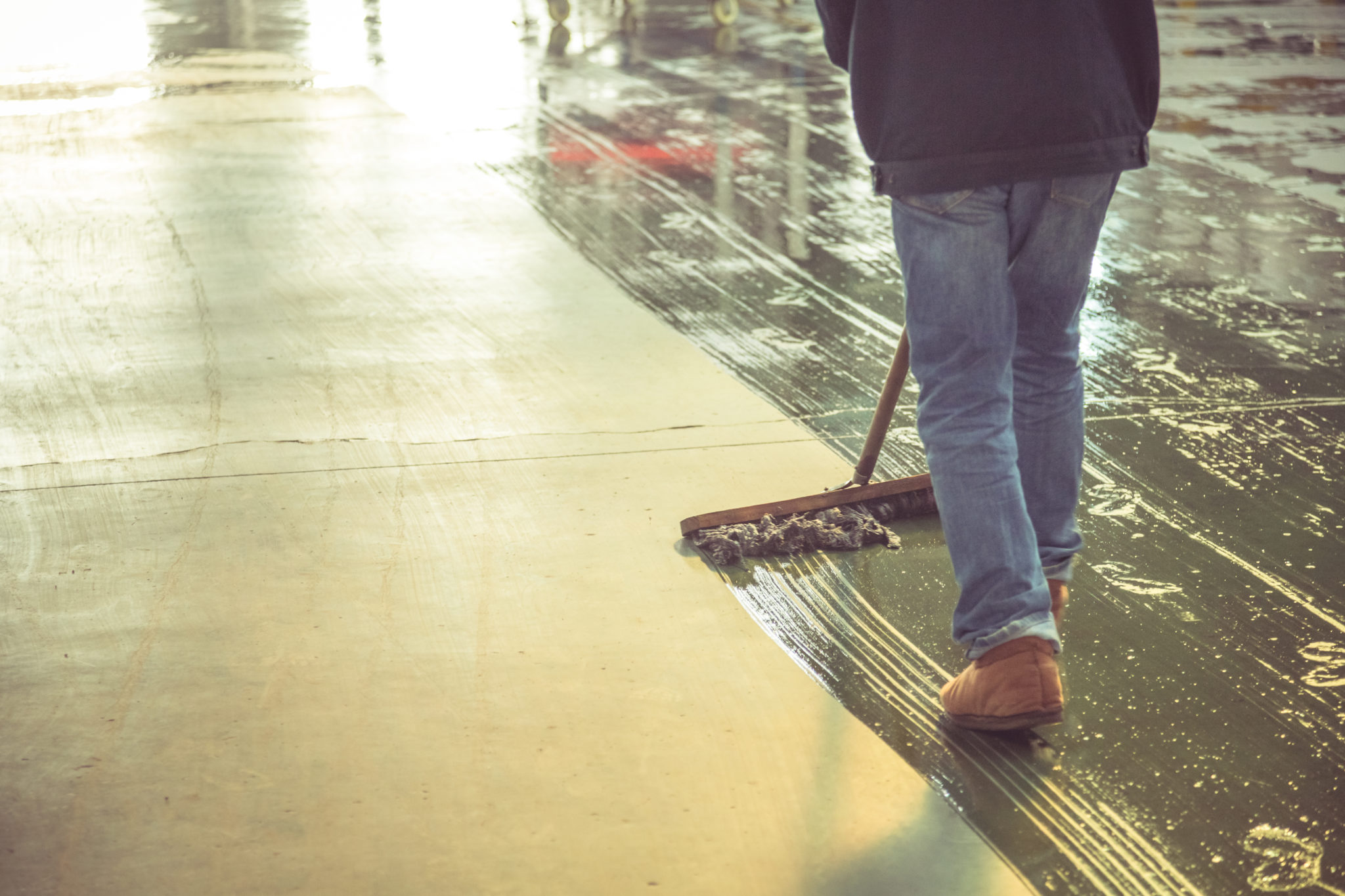 low section of male worker mopping the concrete floor in factory Kryton