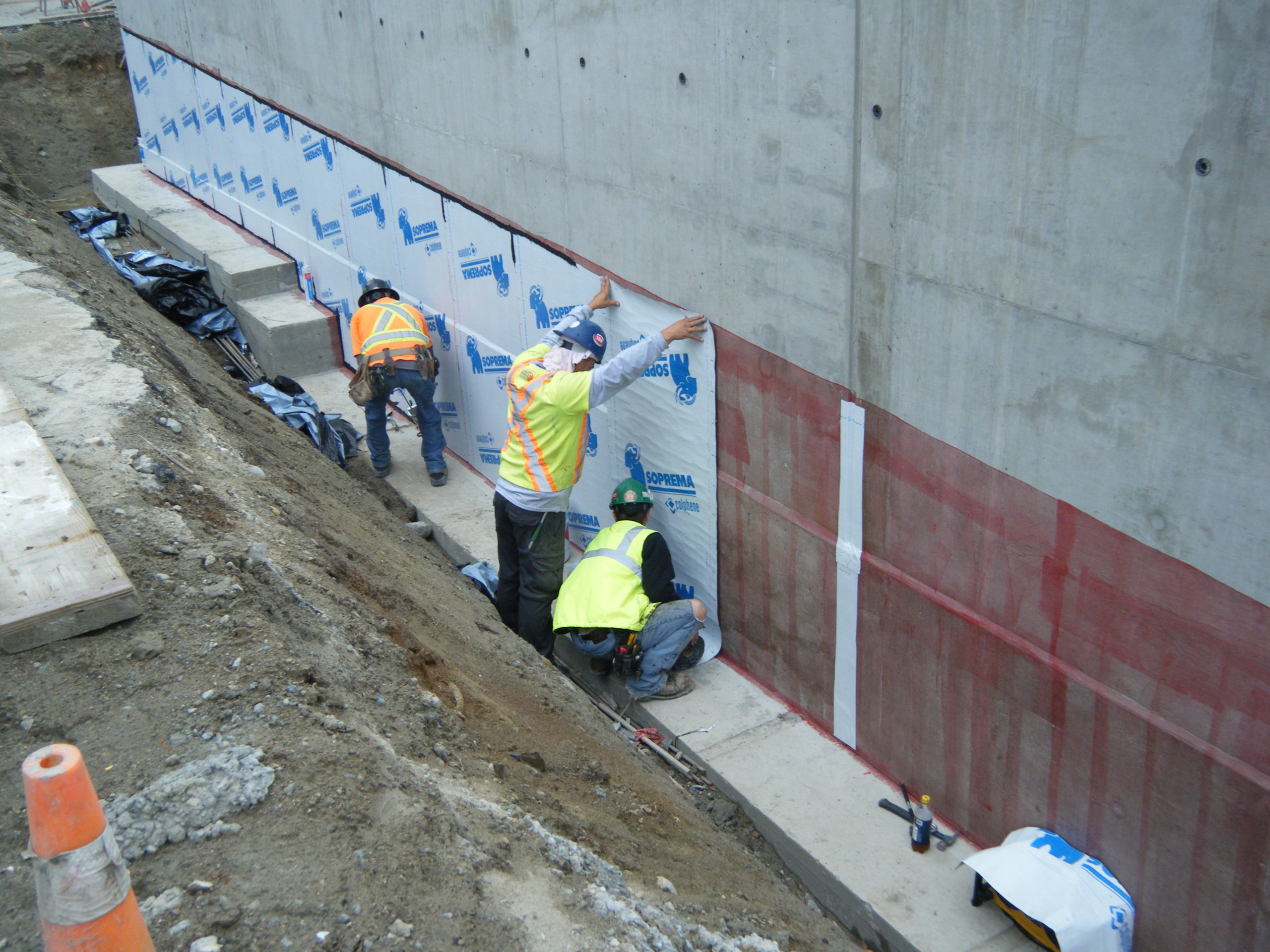 Some construction workers are applying a waterproofing membrane together.