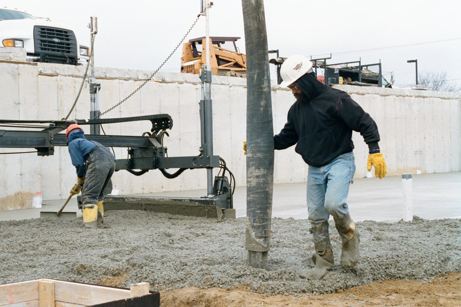 A construction worker is pouring concrete in the winter.