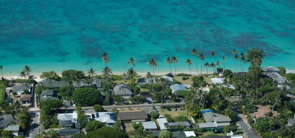 A vast ocean sits before numerous homes on a Hawaiian island that have had floodproofing.