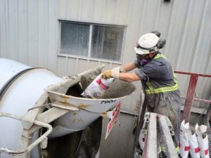 A construction worker is adding the VOC-free Hard-Cem directly into the concrete mix.