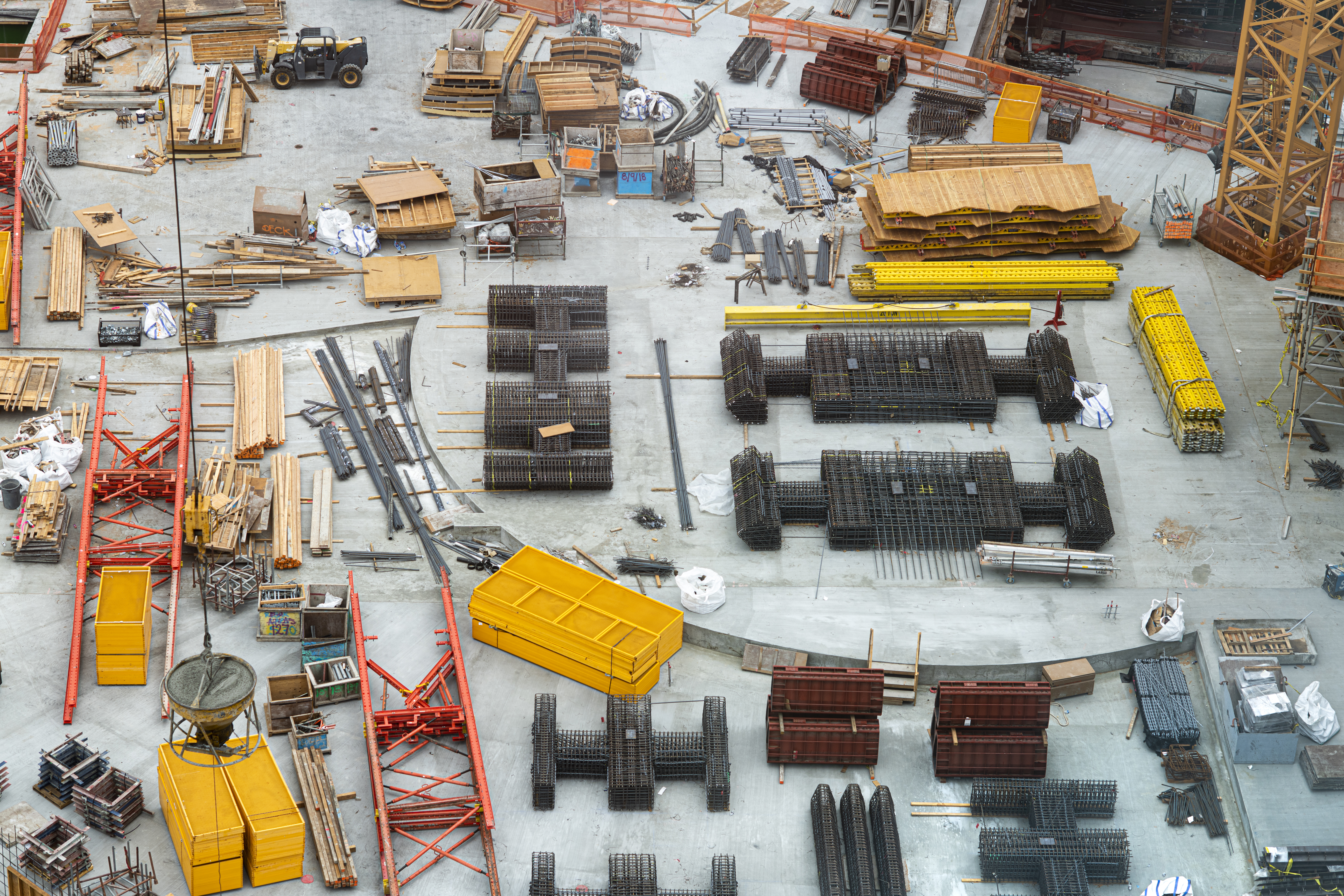 A wide array of construction materials, including wood and steel, are laid out on the ground of a worksite.