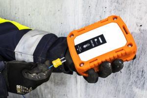 A construction worker is holding a Maturix Sensor in one hand and a thermocouple cable in the other hand.