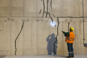 A tunneling engineer is inspecting cracks in tunnel walls.
