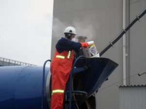 A construction worker is pouring KIM into concrete at the time of batching.