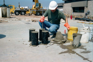 A construction worker is making cylinder concrete samples for testing.