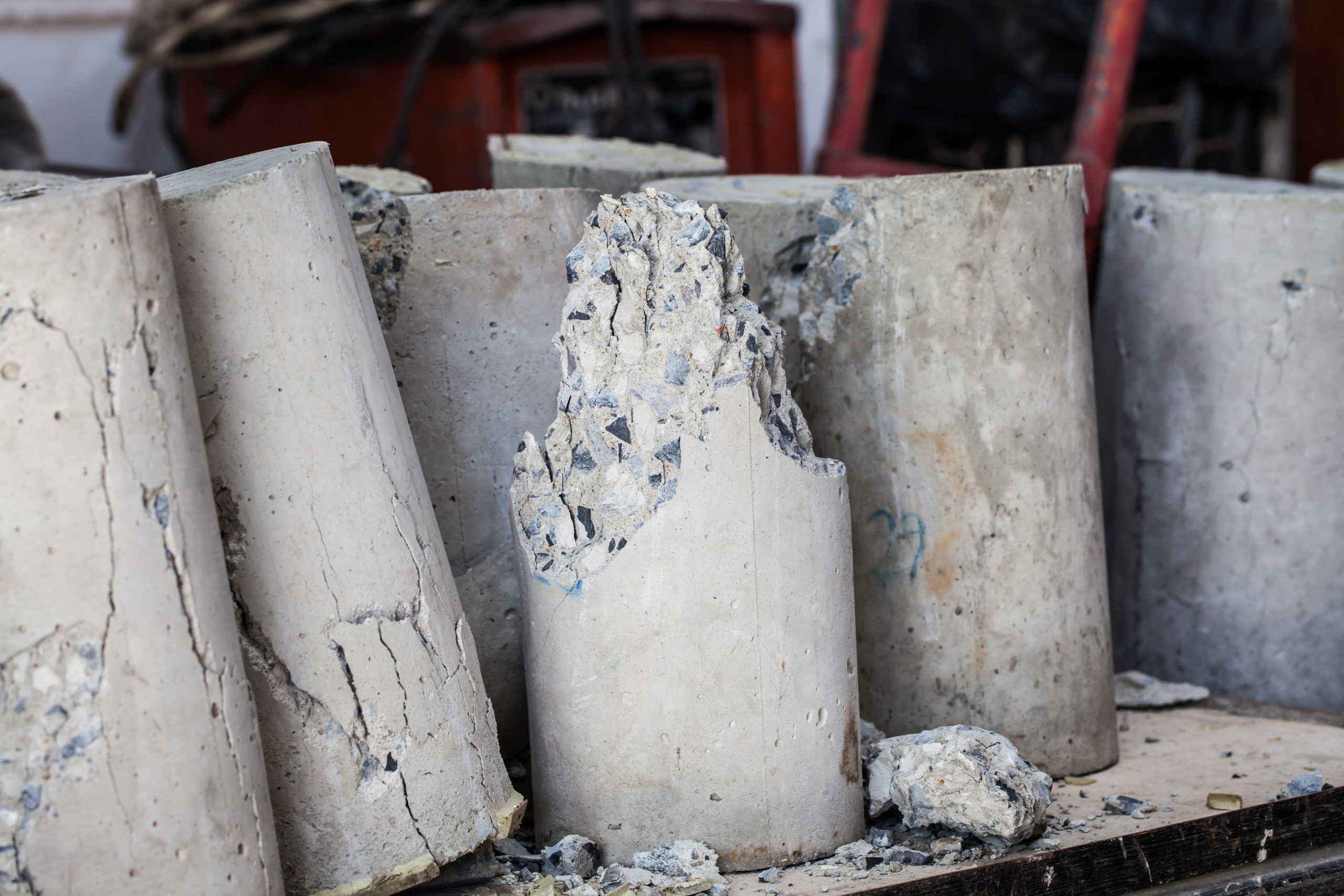 A cluster of concrete cylinder samples rest together on a table with a cracked sample in the middle.