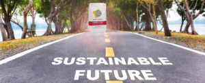 A road is surrounded by grass, trees, and one lawn chair has the words "Sustainable Future" on it, and it leads to an illuminated Hard-Cem package, which is meant to help sustainable construction.