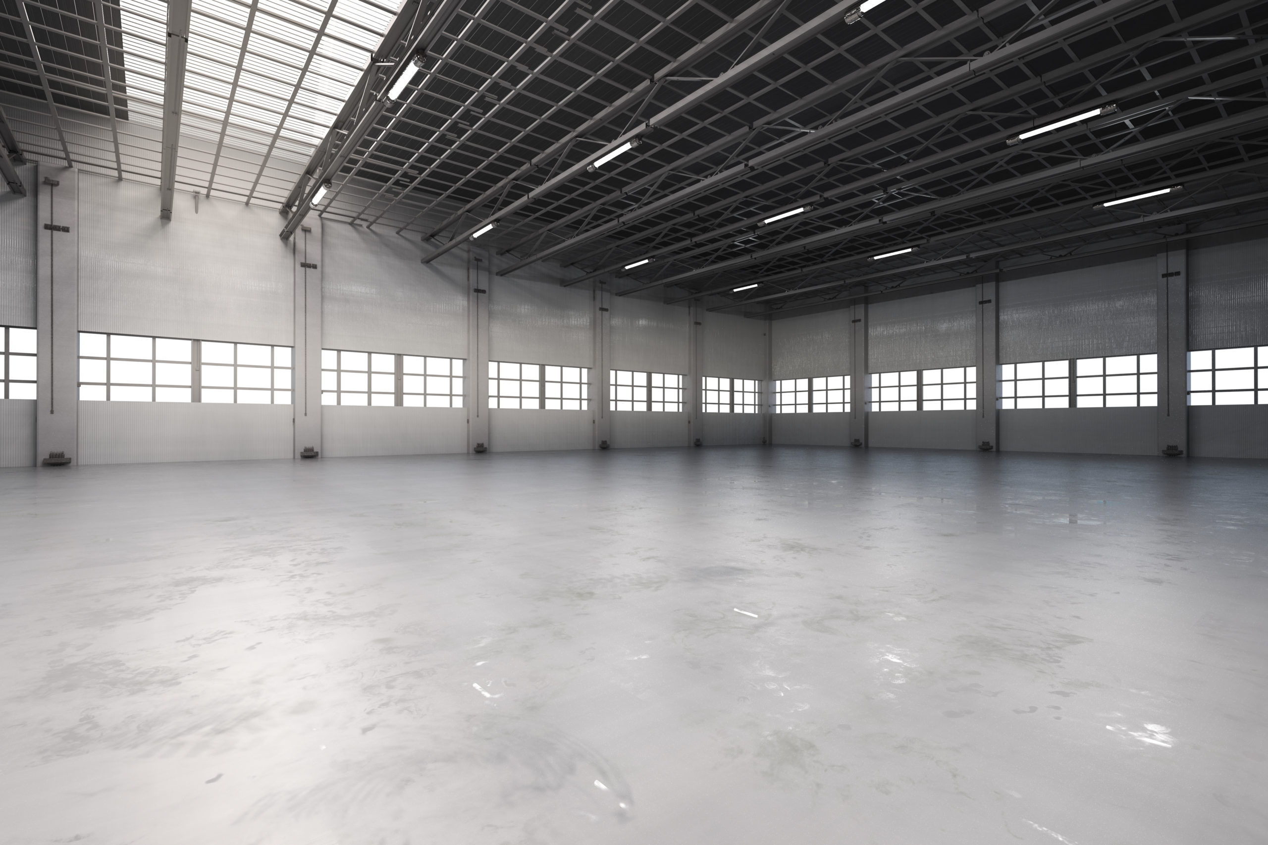 Lights glare over the floor of a concrete warehouse that has yet to undergo warehouse optimization.