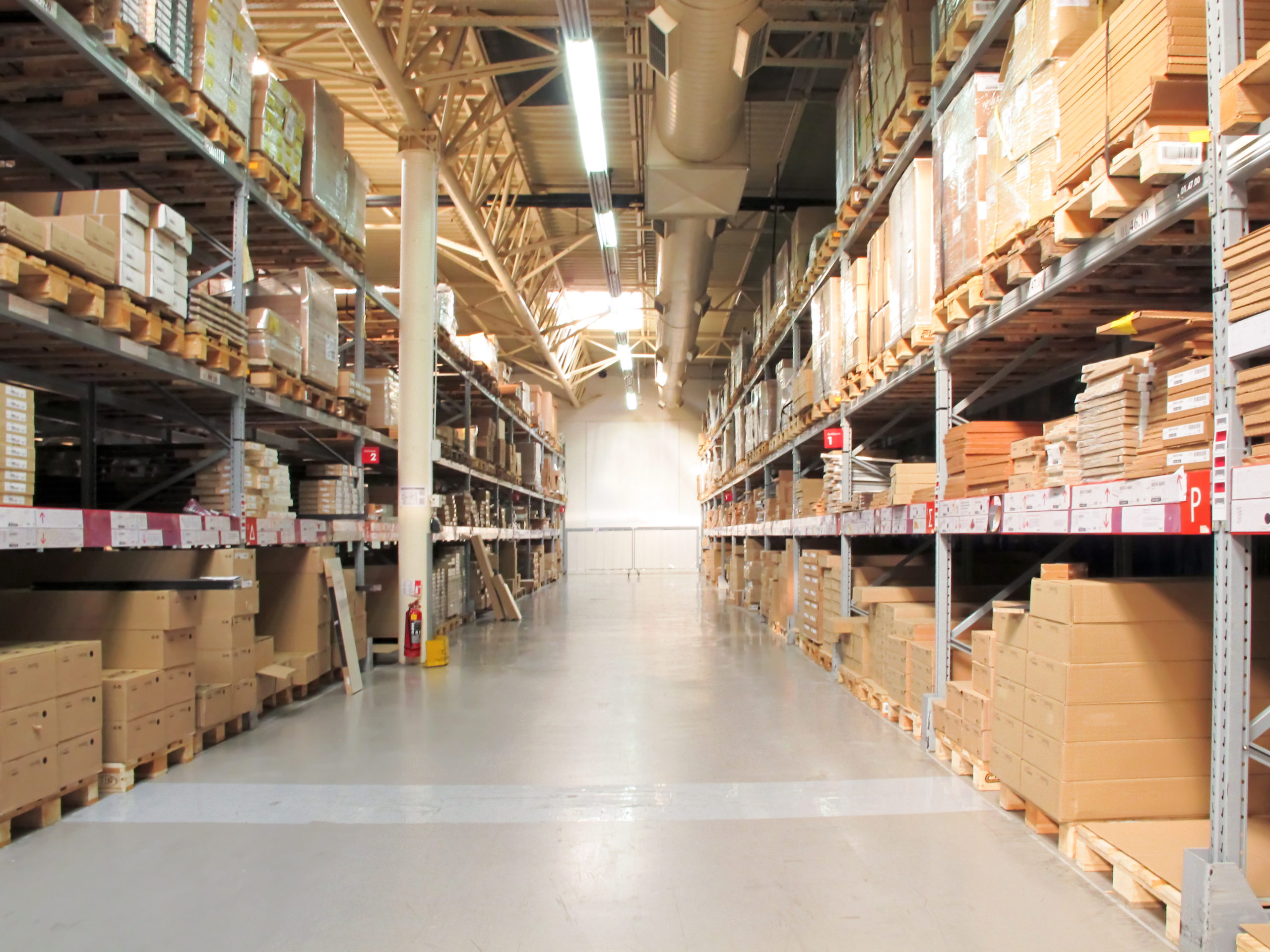 A concrete floor divides two rows of warehouse storage shelves.