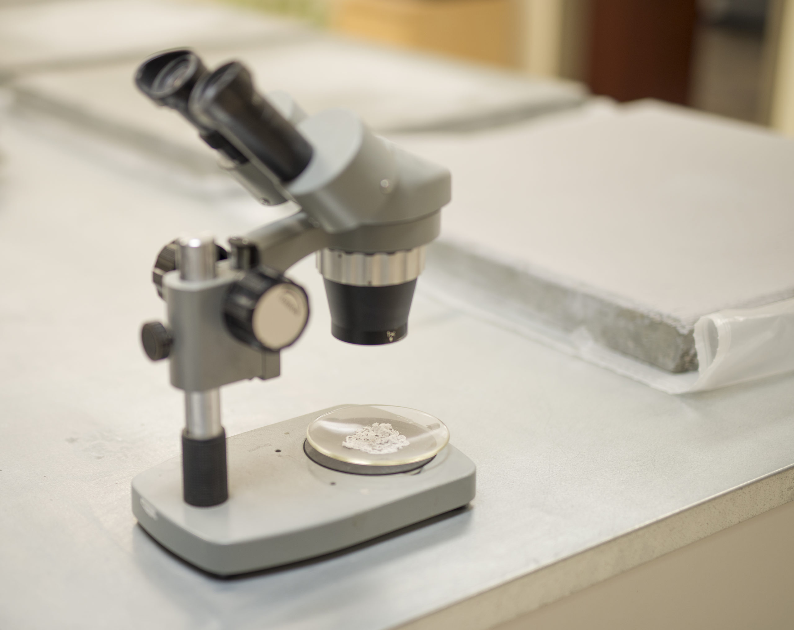A microscope can be seen looking at some material, helping to change the future of concrete waterproofing.