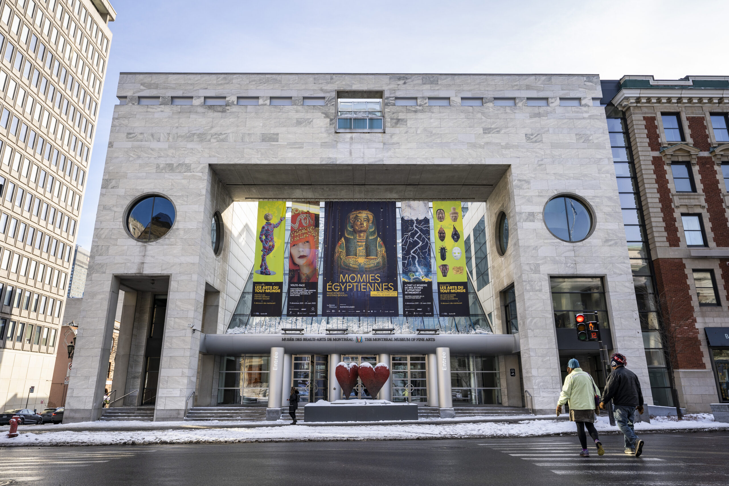 The Moshe Safdie design can be seen straight across the road, presenting a columned portico leading into a triangular glass-roofed lobby with posters above it on the exterior of the building that are advertising several museum exhibitions.