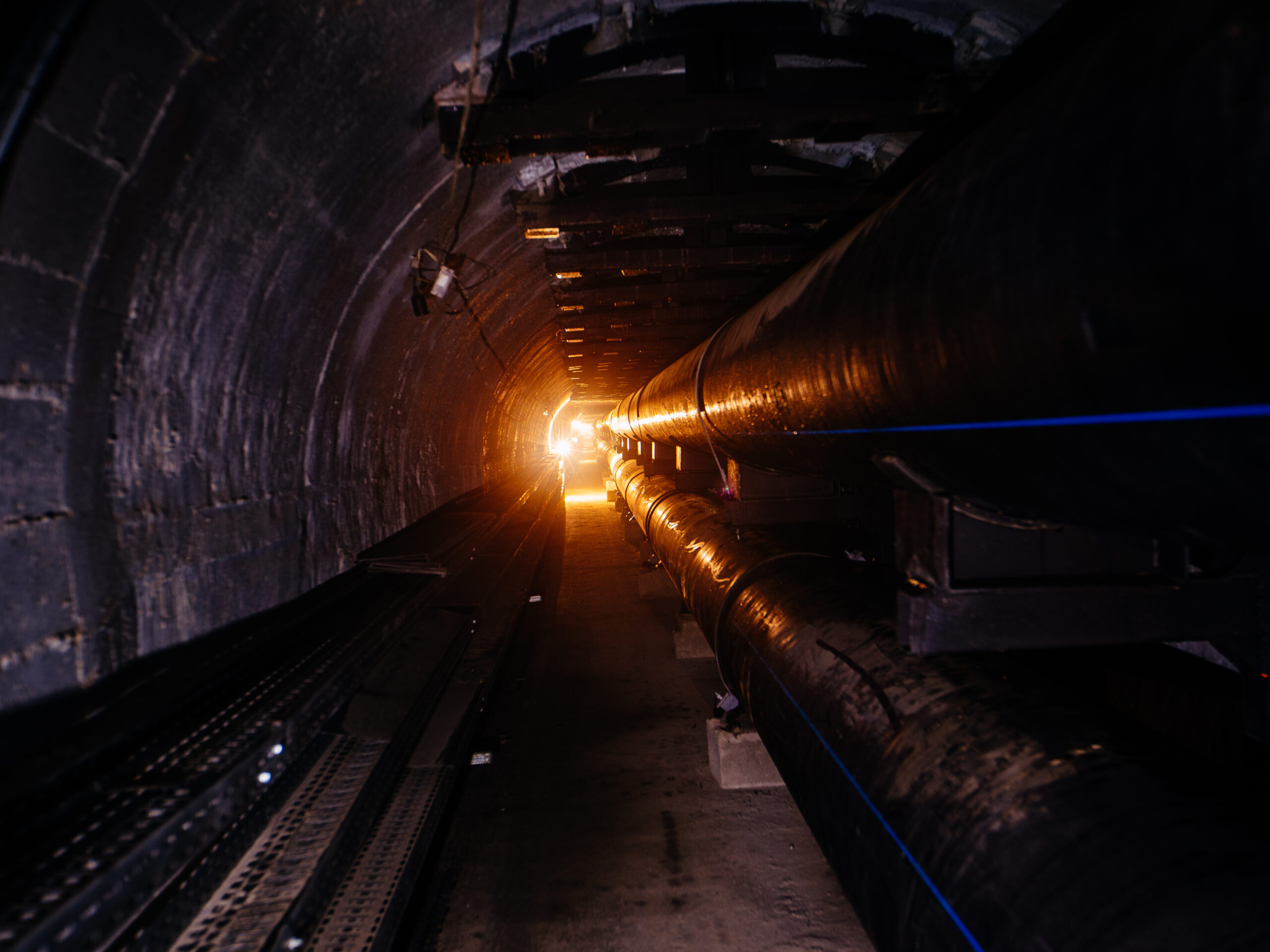 A light is shining up ahead onto an underground aqueduct and sewer system tunnel.